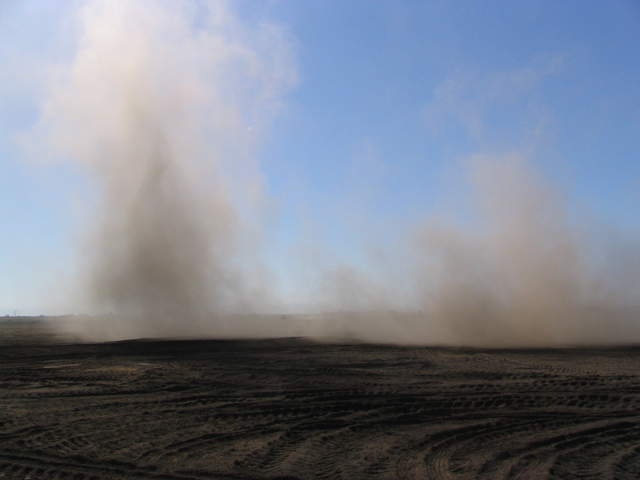 Cloud of dust from tractor tilling field