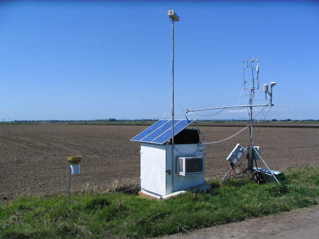 Equipment box and eddy tower next to freshly tilled rice field