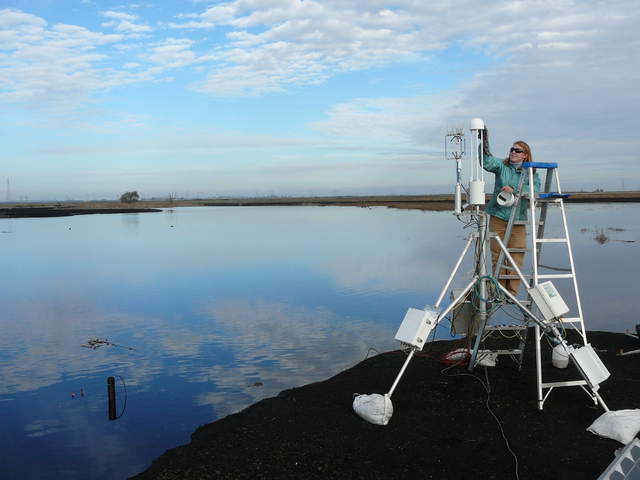 Jaclyn cleaning the eddy sensors with the sky reflected in the water