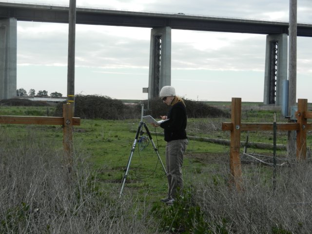 Jaclyn doing spectral measurements at the cow pasture with the bridge in the background