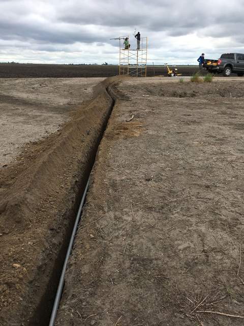 We used a rented trencher to dig a 12in deep trench from the northwest corner of the porch, just past the end of a north-south drainage ditch to the tower location. It crosses both roads at a diagonal. The power cable (two conductor #10 with ground UF-B direct burial cable) is in 3/4in plastic conduit at the bottom of the trench. 