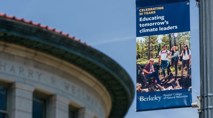 A building with a banner hanging on a pole in front of it that has a picture of researchers and says "Educating Tomorrow's Leaders"