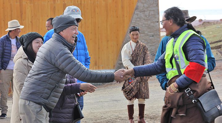 Two people shaking hands with more people in the background. 