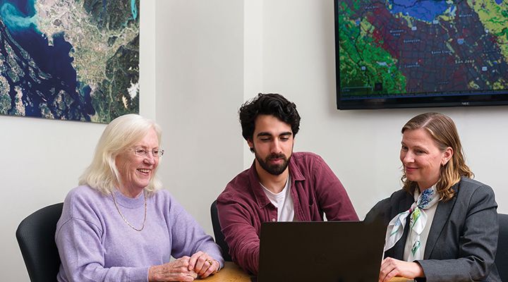 Three people looking at a laptop